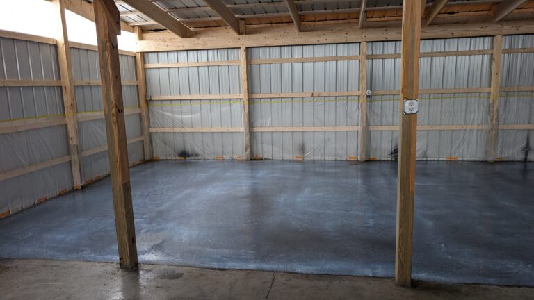 Interior corner view of pole barn with freshly poured concrete floor and metal siding walls in Rochester NY