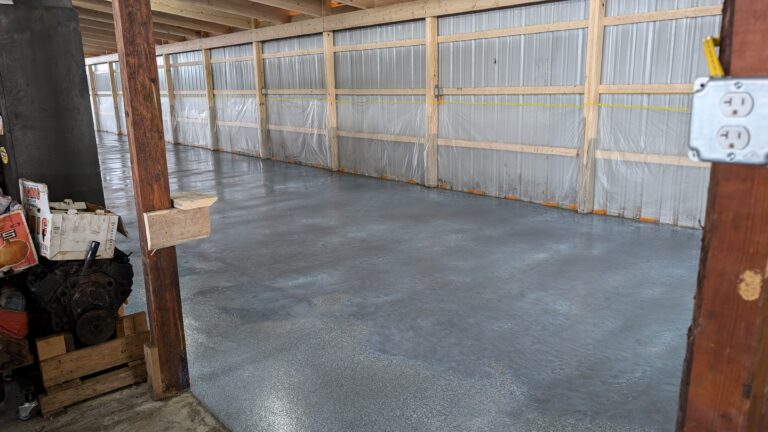 Side view of pole barn concrete floor with vapor barrier walls and support posts in Rochester NY