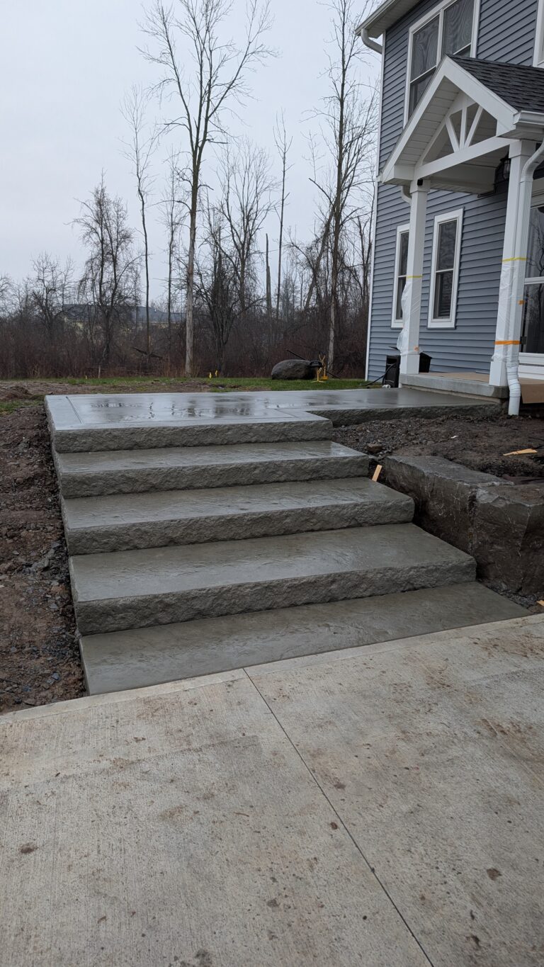 Four wide natural stone entry steps with rough chiseled face risers at new construction home, Rochester NY