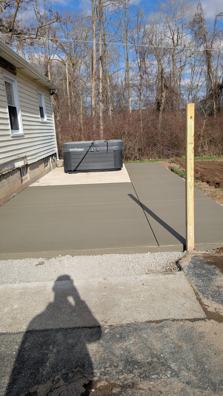 New broomed concrete patio with a dedicated hot tub pad at a Rochester NY residential home
