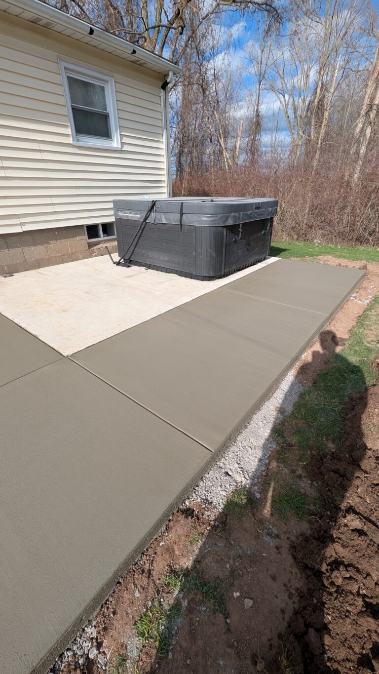 Overhead view of broomed concrete patio with hot tub pad showing broom texture finish at a Rochester NY home