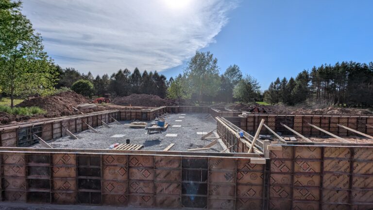 Wide view of full-perimeter poured concrete foundation wall forms assembled for large residential basement – Rochester NY