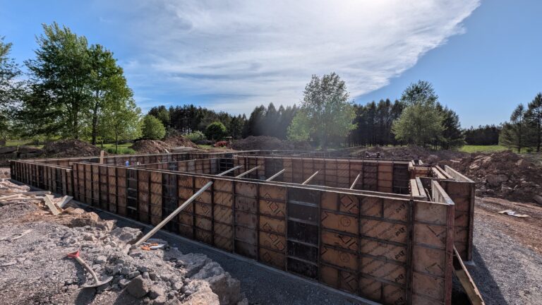 Poured concrete foundation wall forms fully set and braced around residential basement perimeter before pour – Rochester NY