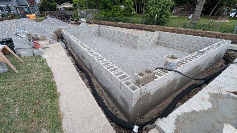 Aerial view of completed CMU block foundation walls with gravel fill and drain tile near waterfront – Rochester NY