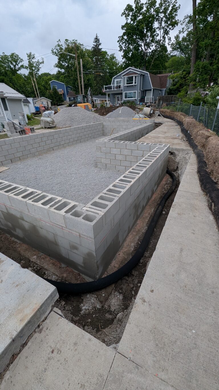 Corner view of CMU block foundation walls with exterior drain tile pipe along perimeter before backfill – Rochester NY