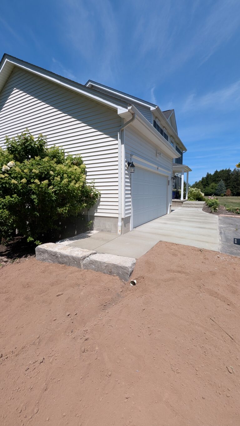 New broomed concrete driveway apron and front walkway at a Rochester NY home with two-car garage