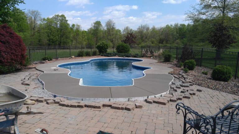 Repaired and newly poured broomed concrete pool deck surround around a freeform in-ground pool in Greece NY