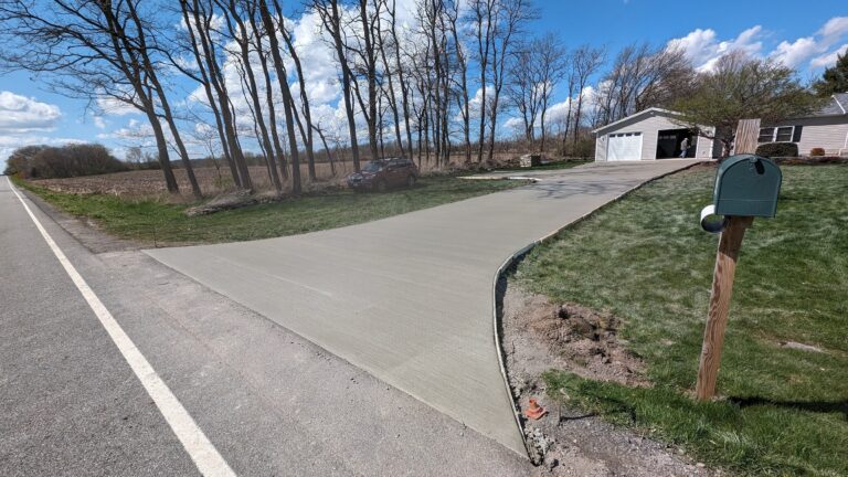 Side view of long broomed concrete driveway from road to garage on rural residential property near Rochester, NY