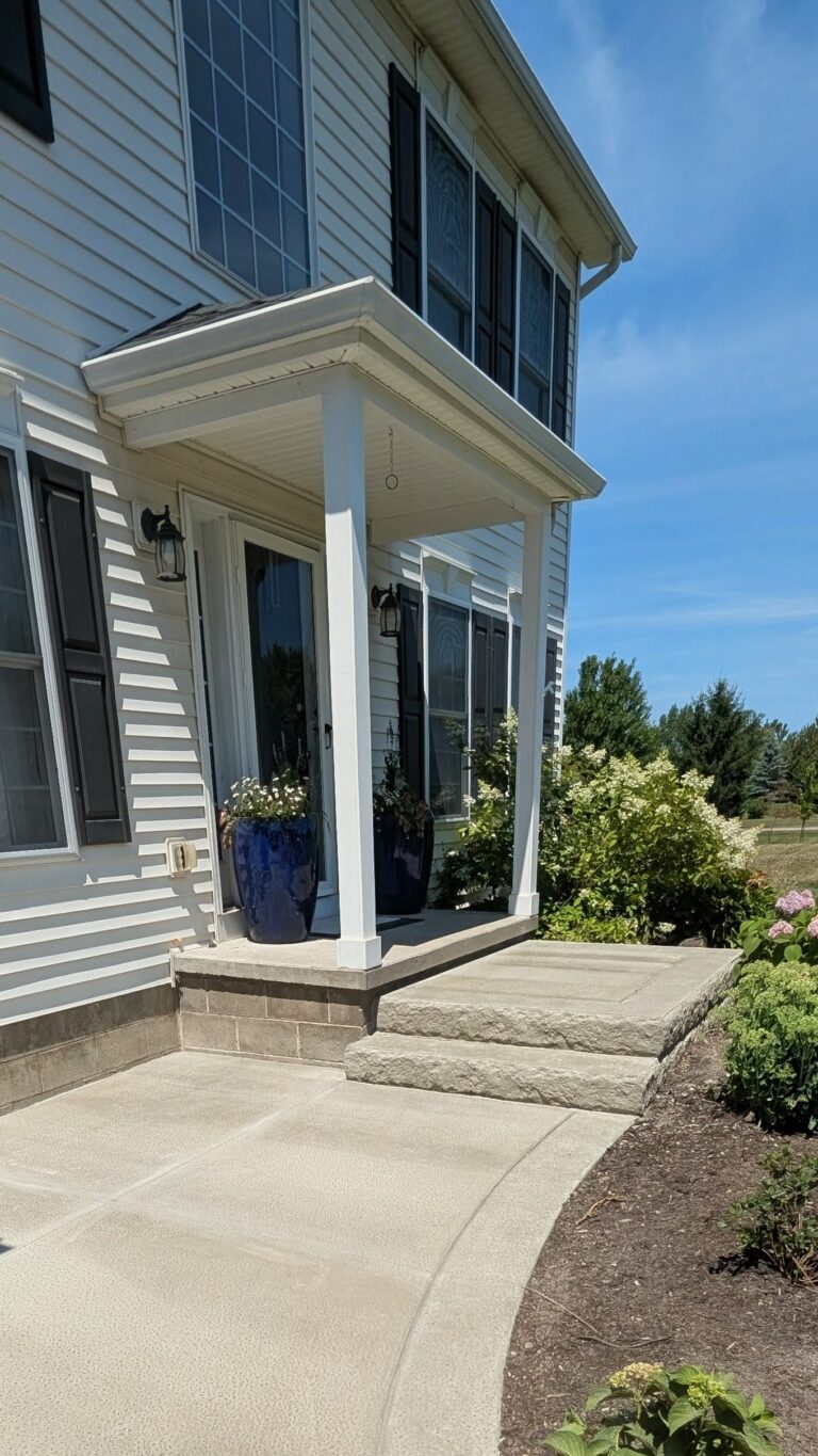 Broomed concrete front entry walkway and covered porch landing with stone steps in Churchville NY