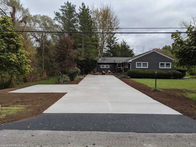 Wide concrete driveway replacement with panel sections and control joints leading to a residential home in Rochester, NY