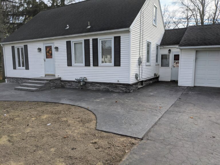Front concrete stoop and driveway with natural stone veneer on home foundation and steps, Rochester NY