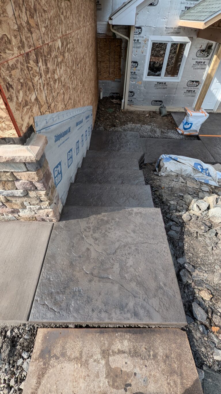 Top-down view of freshly poured stamped concrete entry steps and landing at home under construction – Rochester NY