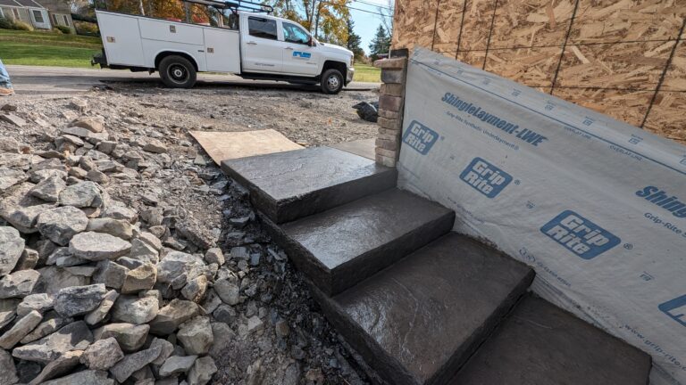 Stamped concrete steps with chiseled risers next to stone veneer pillar at new construction – Rochester NY