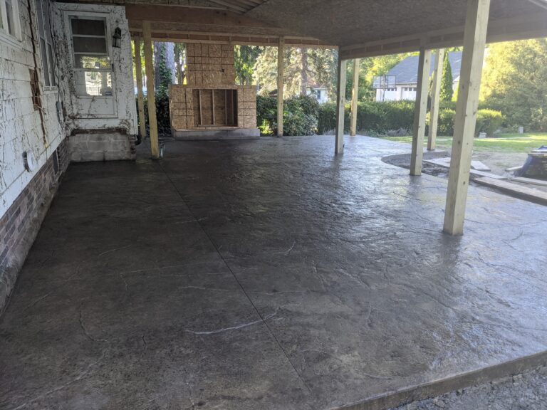 Large stamped concrete patio installed beneath existing deck with walkway extension – Rochester NY